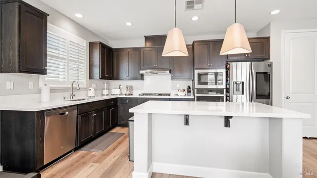 a kitchen with kitchen island granite countertop a sink a stove and cabinets