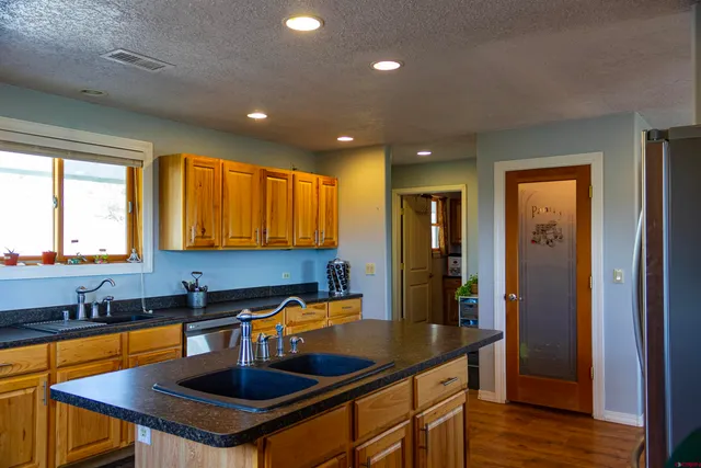 a kitchen with kitchen island granite countertop a sink a counter top space and stainless steel appliances