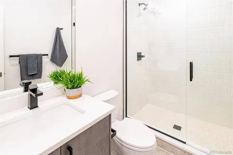 a bathroom with a sink a toilet a glass door a shower and vanity