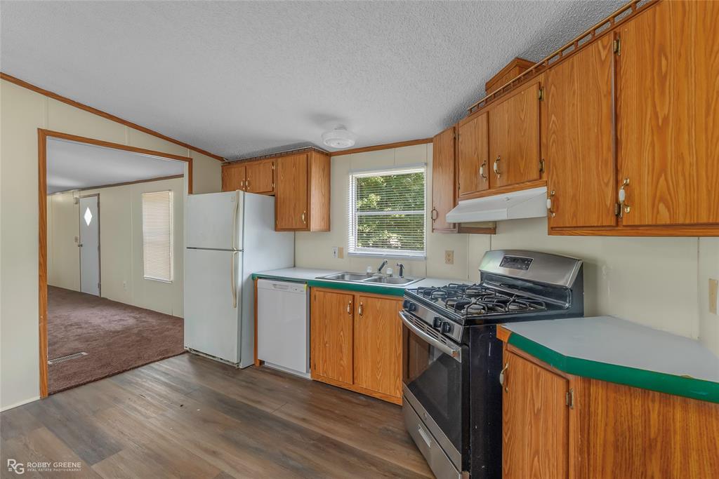 214 Springs Road Frierson, LA 71027 - Photo 11 of 21 a kitchen with stainless steel appliances granite countertop a refrigerator a sink dishwasher and wooden cabinets with wooden floor