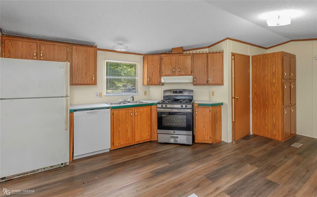 214 Springs Road Frierson, LA 71027 - Photo 8 of 21 a kitchen with stainless steel appliances granite countertop a refrigerator a sink dishwasher a stove with wooden floor and cabinets