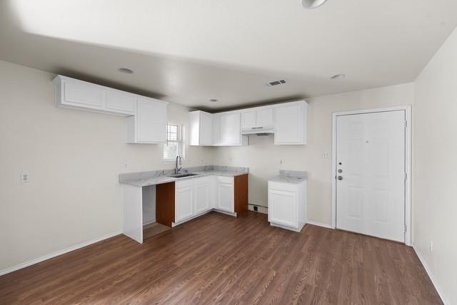 13741 Biggs Street Dallas, TX 75253 - Photo 7 of 17 a kitchen with wooden floors and white cabinets