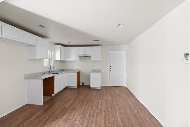 13741 Biggs Street Dallas, TX 75253 - Photo 9 of 17 a kitchen with wooden floors and white cabinets