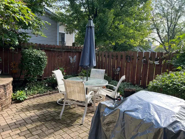 a view of backyard with table and chairs potted plants and wooden fence