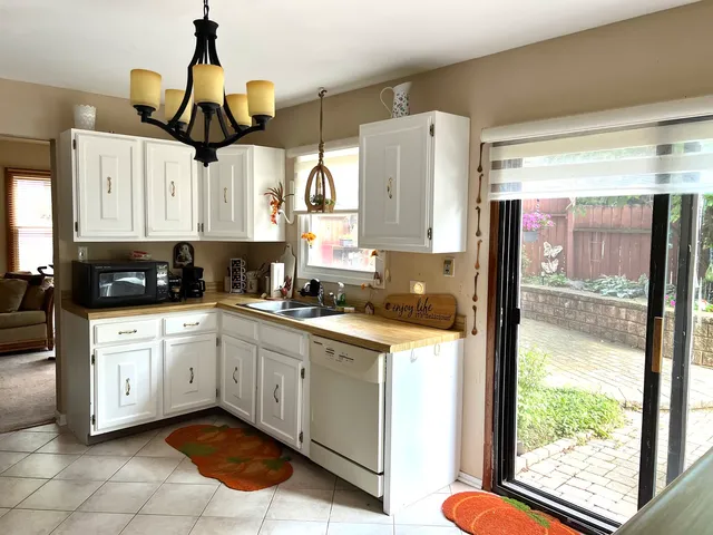 a kitchen with stainless steel appliances a sink a counter top space cabinets and a chandelier