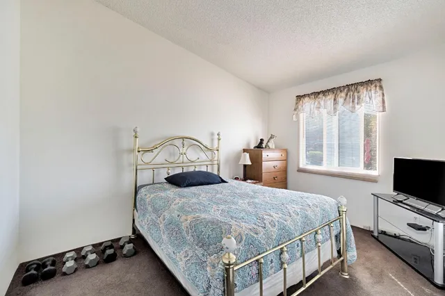 a bedroom with a bed and a flat tv screen on the dresser