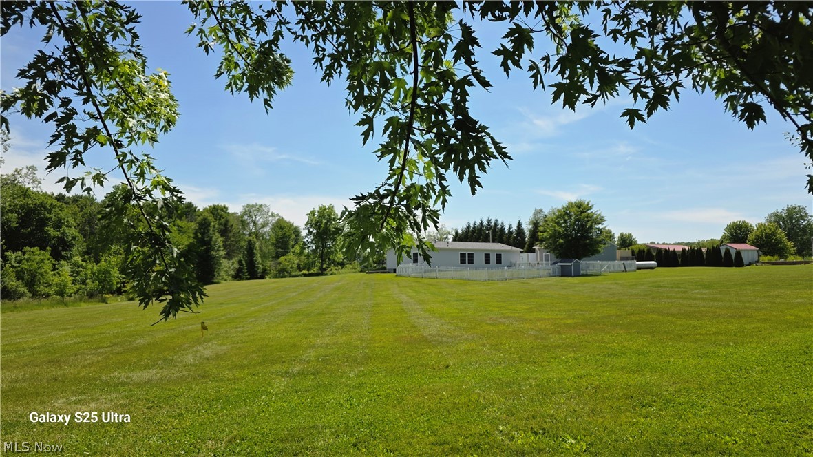 294 Twp 150 Road Sullivan, OH 44880 - Photo 37 of 39 Expansive green lawn with a white single-story residence in the background, featuring a white picket fence, mature trees, and an additional storage shed