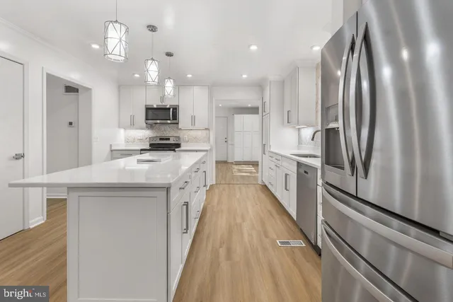 a kitchen with stainless steel appliances granite countertop a refrigerator a stove and a sink with wooden floor