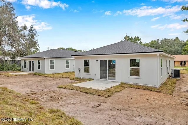a front view of a house with a dirt yard and a tree