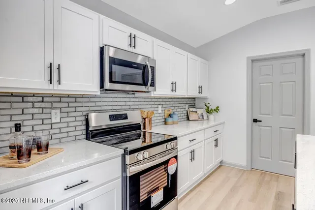 a kitchen with stainless steel appliances white cabinets and stove top oven