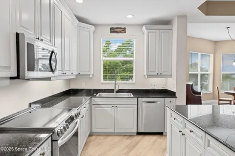 a kitchen with granite countertop a sink a window stainless steel appliances and cabinets