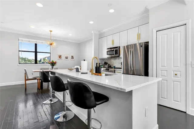 a kitchen with stainless steel appliances a sink a stove a refrigerator cabinets and a dining table with wooden floor