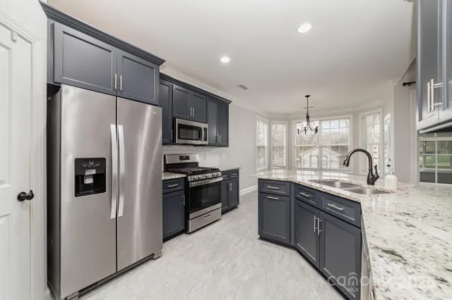a kitchen with stainless steel appliances granite countertop a sink stove and refrigerator