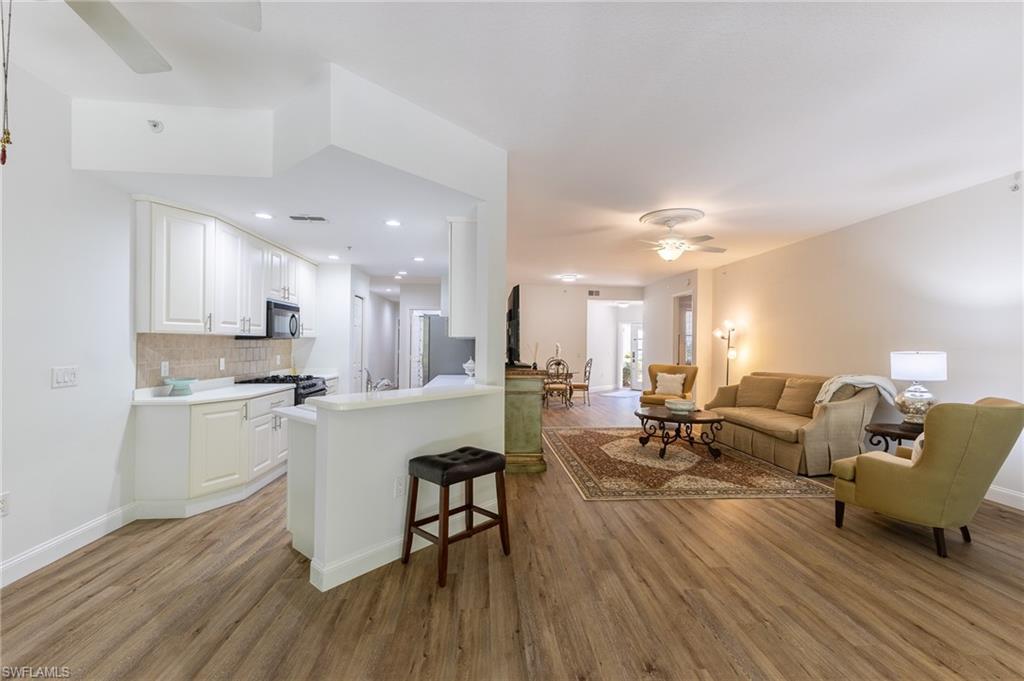 3975 Deer Crossing Court, Unit 102 Naples, FL 34114 - Photo 20 of 32 a living room with furniture and a wooden floor