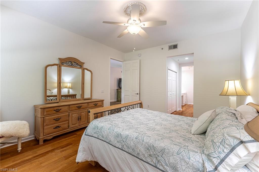 3975 Deer Crossing Court, Unit 102 Naples, FL 34114 - Photo 27 of 32 a bedroom with a bed and a chandelier