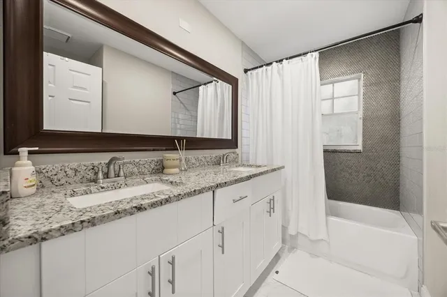 a bathroom with a granite countertop sink and a bathtub