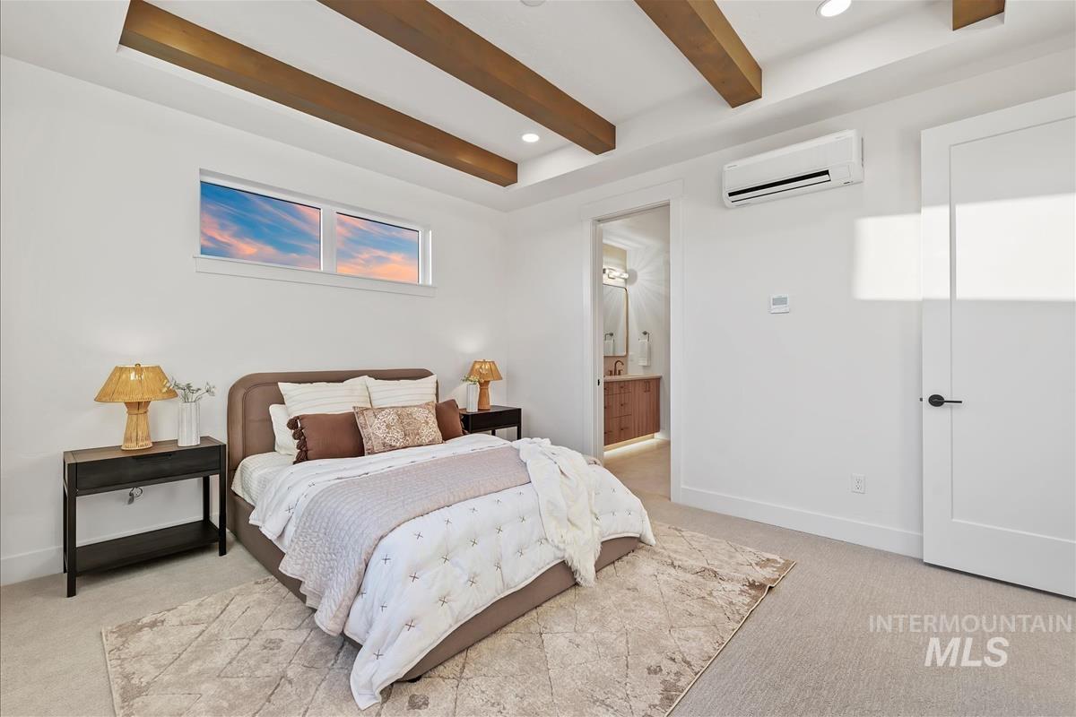 3219 West Moore Street Boise, ID 83702 - Photo 20 of 36 Bedroom featuring overhead wood beams, a horizontal window, wall-mounted climate control, and an open doorway leading to a bathroom with a vanity