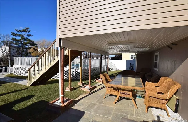 a view of a patio with table and chairs potted plants with wooden floor and fence