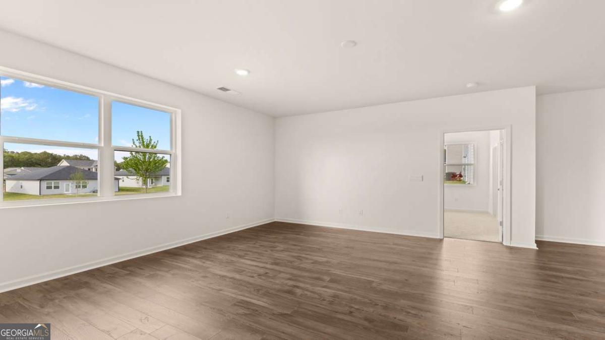 8576 Seabiscuit Road Lithonia, GA 30058 - Photo 6 of 22 an empty room with wooden floor and windows