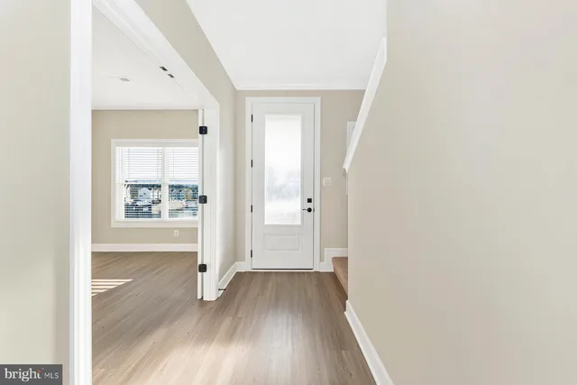 a view of a hallway with wooden floor and a bathroom