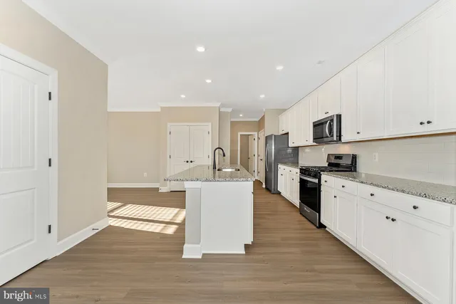 a large white kitchen with wooden floor and stainless steel appliances