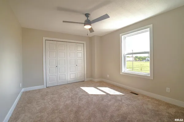 en empty room with windows and chandelier fan