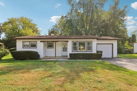 a view of a house with a yard and lawn chairs with a fire pit