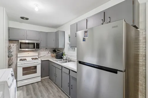 a white refrigerator freezer and a stove sitting inside of a kitchen with stainless steel appliances granite countertop cabinets and a refrigerator
