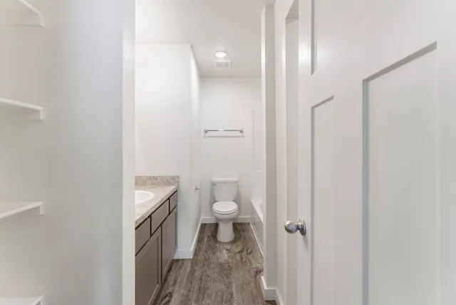 a bathroom with a granite countertop toilet and a sink