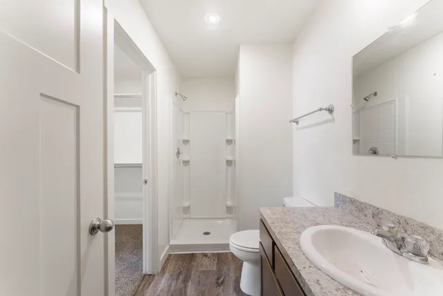 a bathroom with a granite countertop toilet a sink and a mirror
