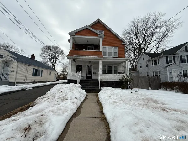a front view of a house with a yard covered in snow