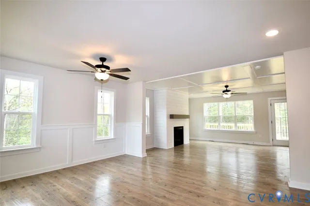 a view of an empty room with a window and wooden floor