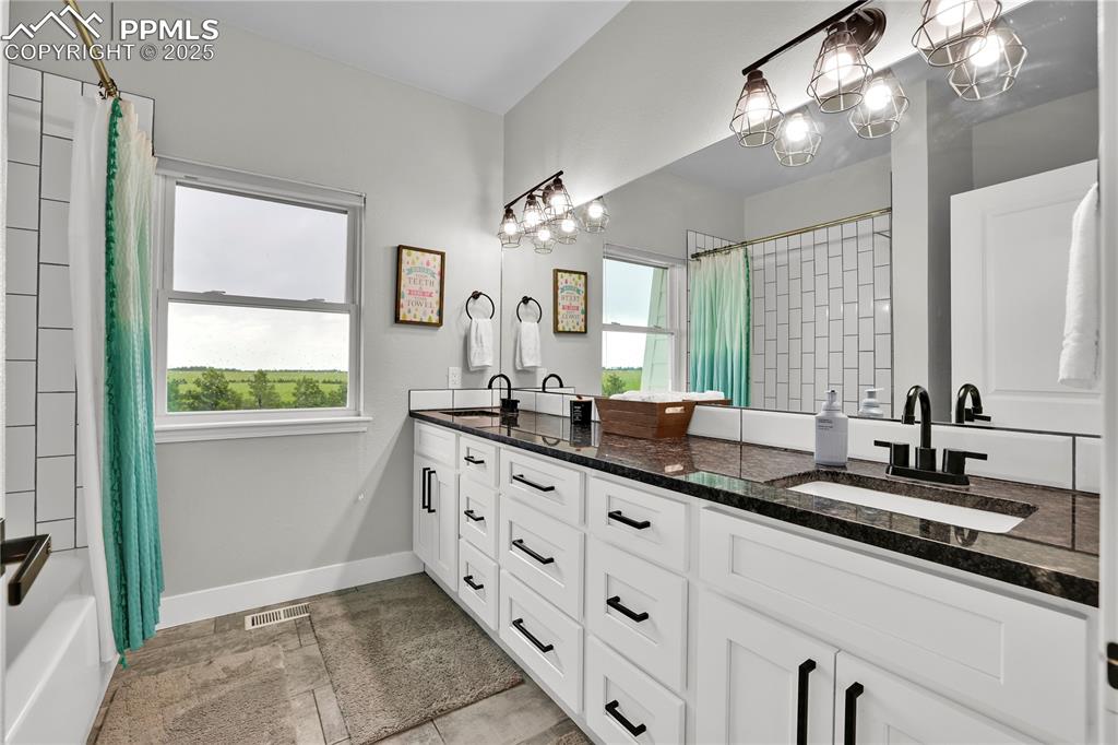18135 Spur Ranch Road Peyton, CO 80831 - Photo 26 of 36 a bathroom with a double vanity sink and a mirror