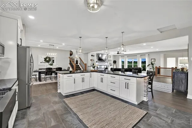 a kitchen with stainless steel appliances kitchen island granite countertop a stove a sink a oven a dining table and chairs with wooden floor