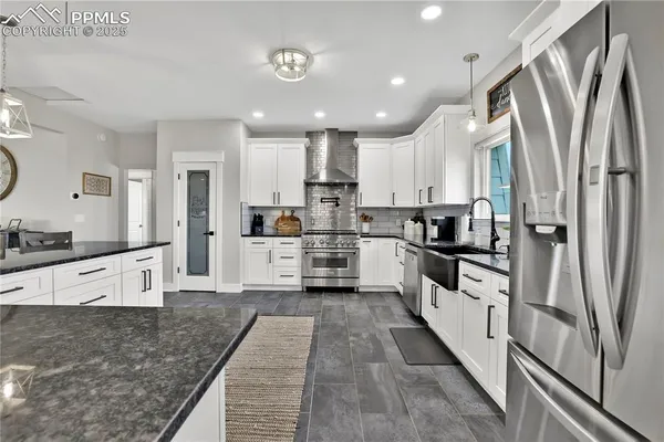 a kitchen with stainless steel appliances granite countertop a refrigerator sink and white cabinets