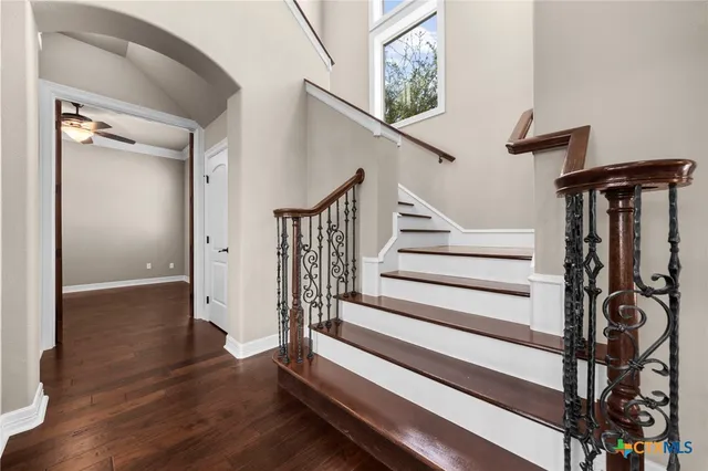 a view of a big room with wooden floor a ceiling fan and a kitchen view