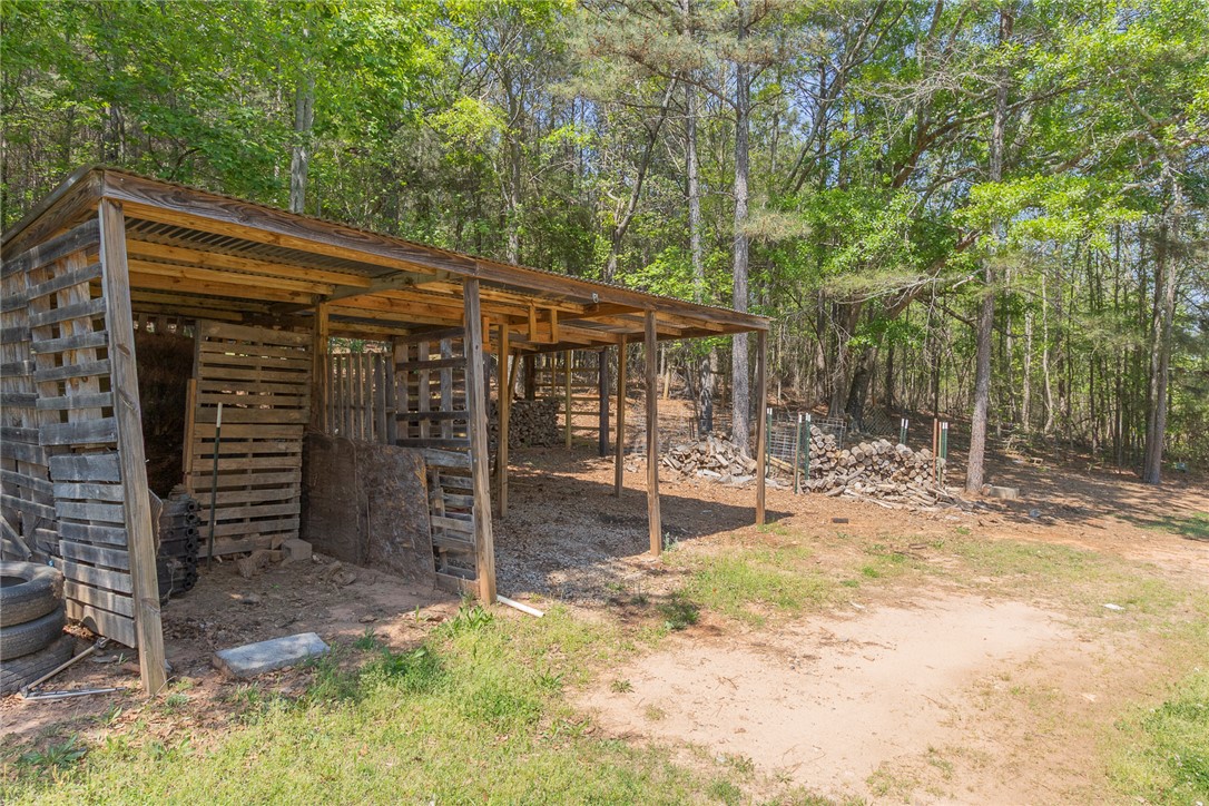 820 Travis Road Anderson, SC 29626 - Photo 40 of 46 This rustic shelter offers practical outdoor storage amidst a serene, wooded backdrop.