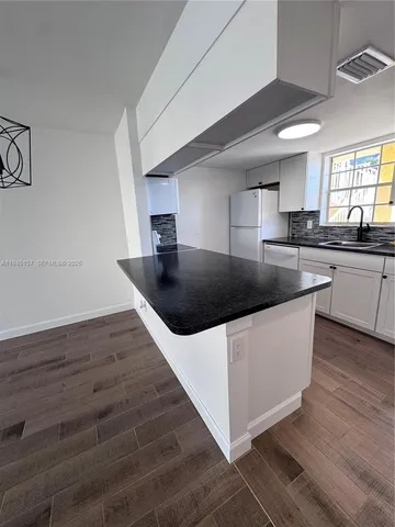 a view of a kitchen with wooden floor and electronic appliances