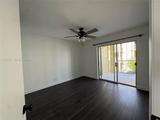 an empty room with wooden floor and windows with curtains