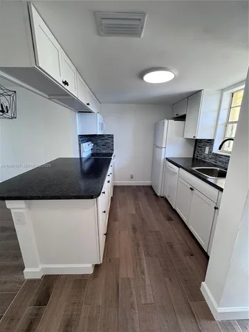 a kitchen with granite countertop a stove and a wooden floor