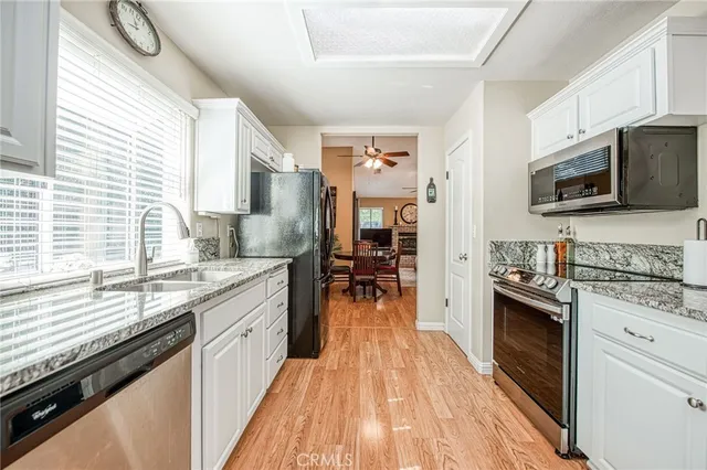 a kitchen with stainless steel appliances wooden floor sink stove and cabinets