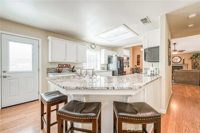 a kitchen with kitchen island granite countertop a dining table chairs cabinets and wooden floor