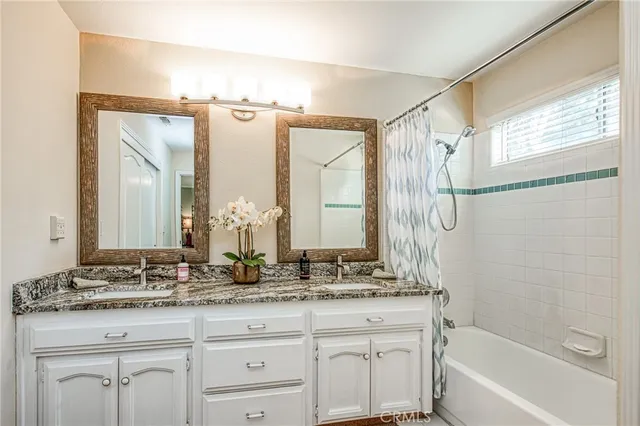 a bathroom with a granite countertop sink a mirror and a bathtub next to a window