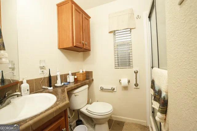 a bathroom with a granite countertop toilet sink and mirror