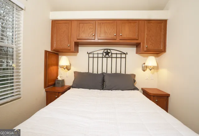 a kitchen with a white bed and cabinets