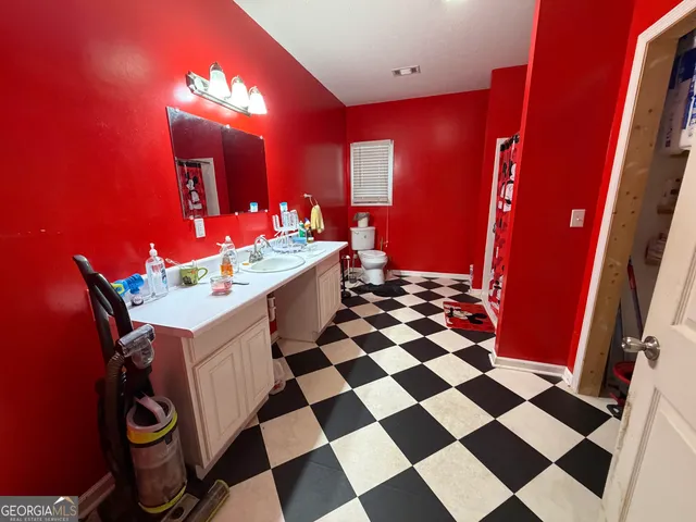 a living room with a black white checkered floor with a gaming machine and dining table