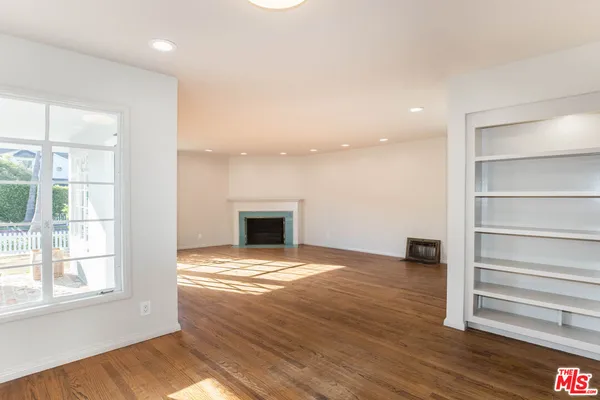 a view of empty room with wooden floor and fireplace