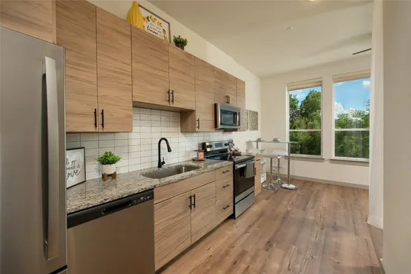 a kitchen with stainless steel appliances granite countertop a sink stove and wooden floor