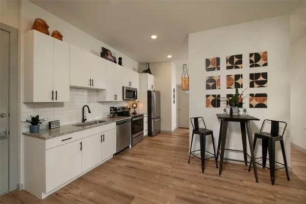 a kitchen with stainless steel appliances kitchen island granite countertop a table chairs refrigerator and sink