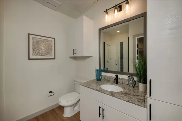 a bathroom with a granite countertop sink toilet and mirror